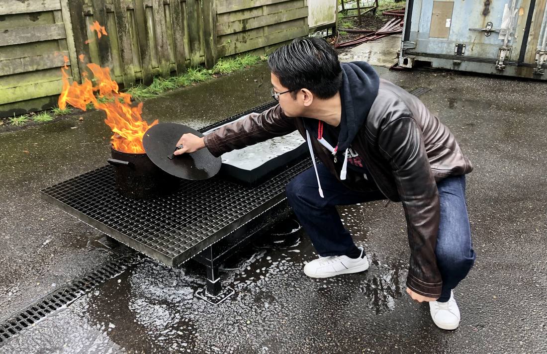 Cursist dooft tijdens een BHV training van LuxBHV een brandende pan door er een deksel op te schuiven