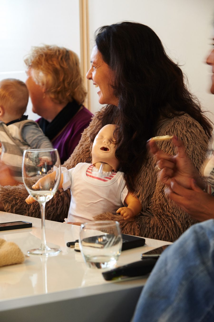 Deelnemer met een oefenpop op schoot tijdens een workshop EHBO bij kinderen aan huis